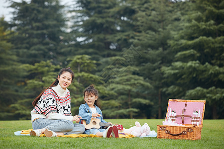 母女在草地上弹尤克里里背景图片