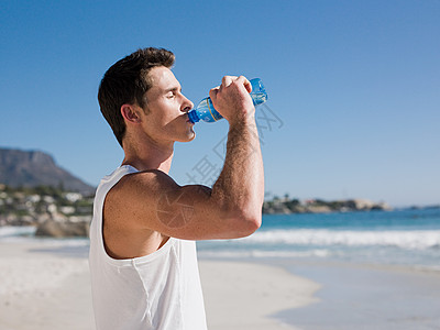 年轻人在海滩上喝水高清图片