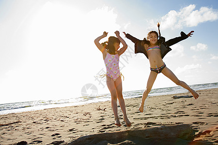 沙滩跳跃女孩女孩们在沙滩上跳背景
