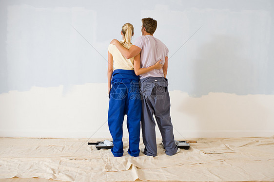 看墙上油漆的夫妇的后视图图片