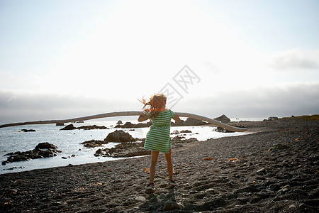 站在海滩上抱着浮木的女孩图片