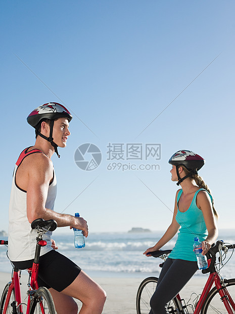 年轻夫妇在海滩骑车图片