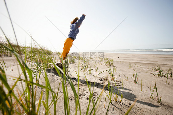 年轻人站在沙滩上的岩石上图片