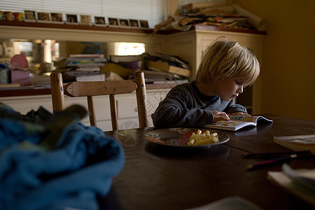 小男孩坐在餐桌旁看书图片