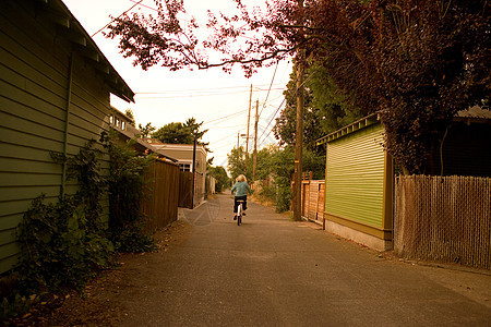 男孩骑着自行车沿着小巷骑行图片
