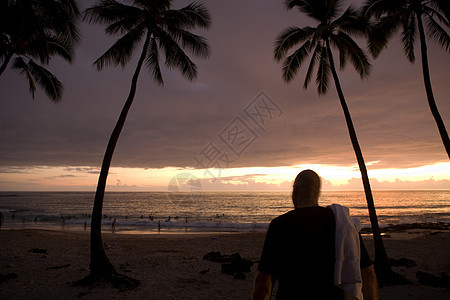 日落时海滩上的男人图片