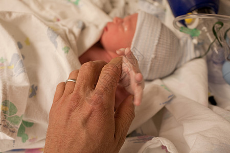 新生男婴握住父母的手指图片