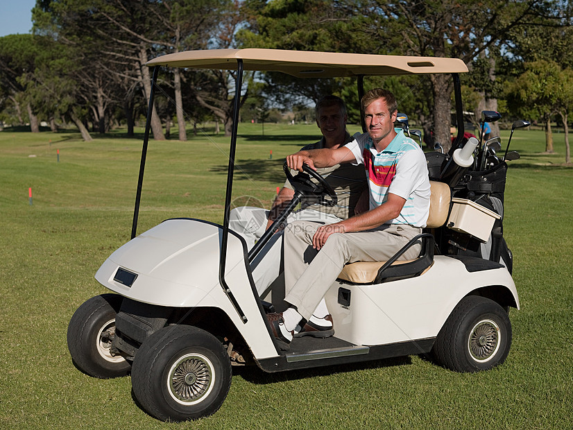 两个中年男性在高尔夫球场的高尔夫球车上图片