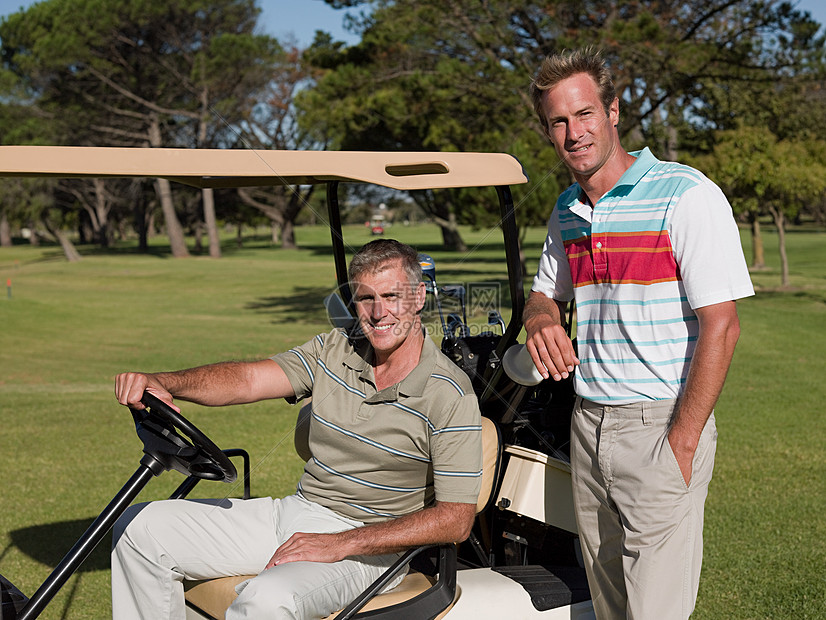 两个中年男子在高尔夫球场的高尔夫球车上图片