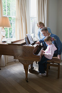 弹钢琴的女孩父母带着女儿弹钢琴背景
