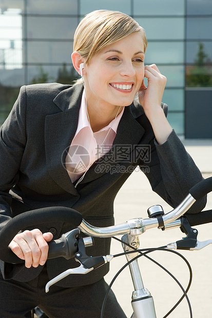 骑自行车带耳机的女商人图片