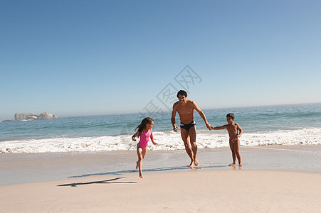 父亲和孩子们在海滩上奔跑图片