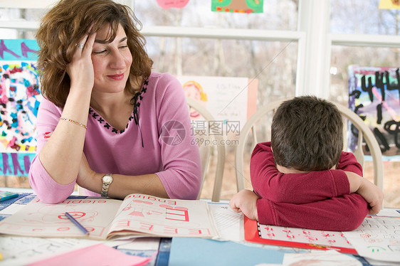 母亲辅助疲惫的儿子做家庭作业图片