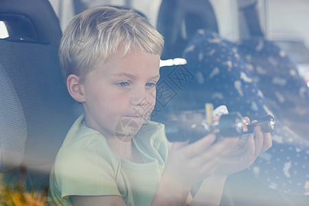 男孩坐在车里抱着玩具车图片