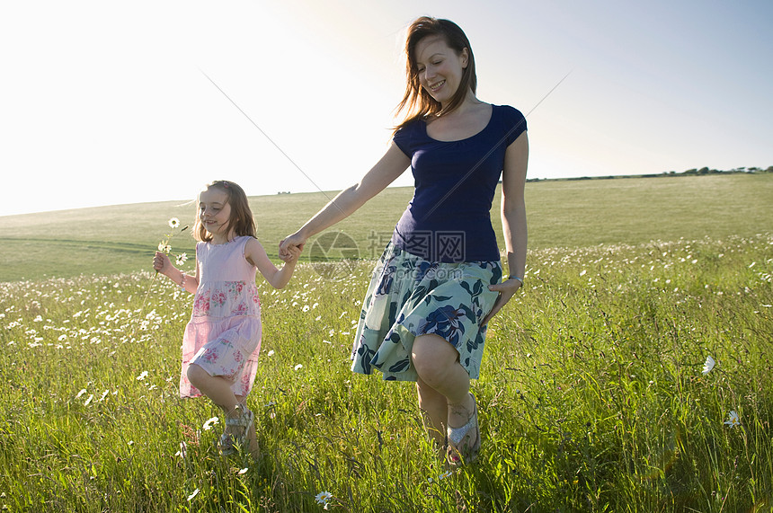 女人和孩子漫步在阳光明媚的草地上图片