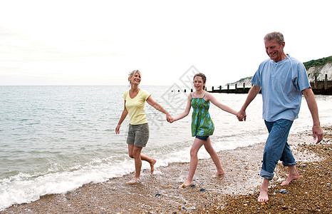 女孩和祖父母在海滩上散步图片
