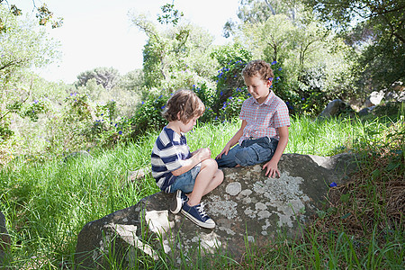 两个男孩坐在石头上图片