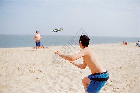 男孩们在海滩上玩飞盘图片