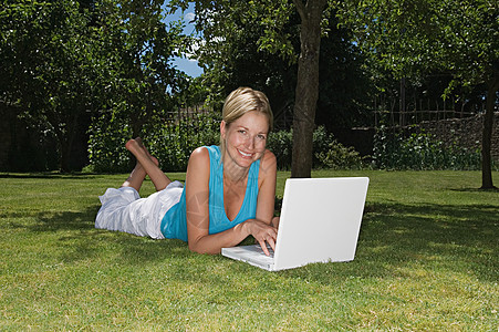 躺在草地上用笔记本电脑的女人图片