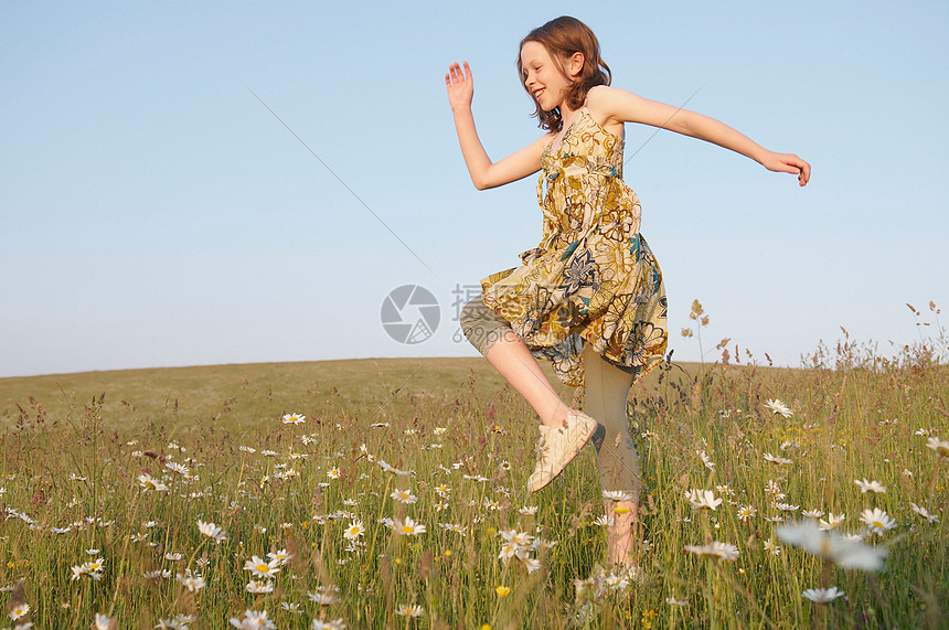 小女孩在草地上蹦蹦跳跳图片