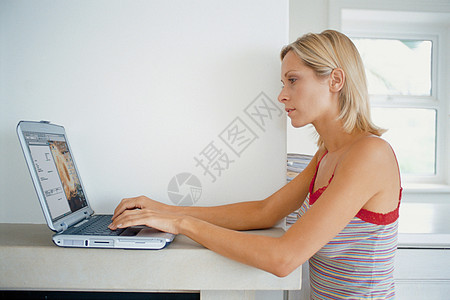 女人在壁炉架上使用笔记本电脑图片
