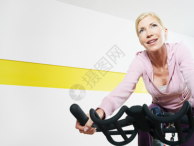 健身俱乐部骑健身自行车的女人图片