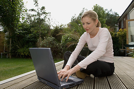 在花园里用笔记本电脑的女人图片