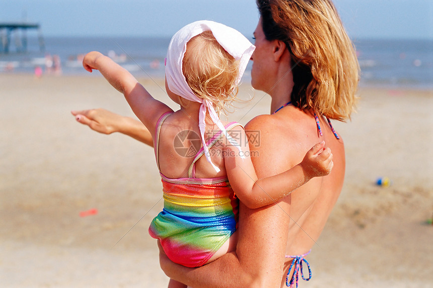 海滩上抱着小孩的女人图片