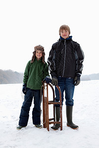 两个男孩站在雪橇旁边图片
