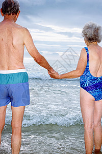 一对老年夫妇在海滩上手拉手图片