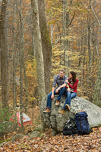 年轻夫妇坐在森林里的巨石上图片