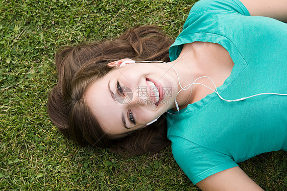 戴着耳机躺在草丛地上的女孩图片