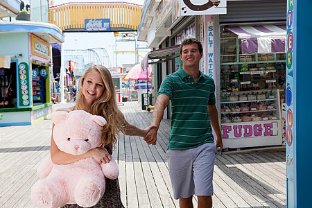 一对十几岁的夫妇抱着泰迪熊走在路上图片