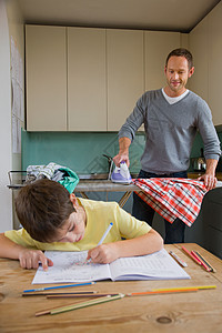 父亲在熨衣服和儿子在做作业图片