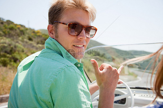 戴着太阳镜驾驶敞篷车的年轻人图片