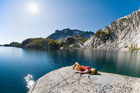 在迷人的湖边晒日光浴的女人图片