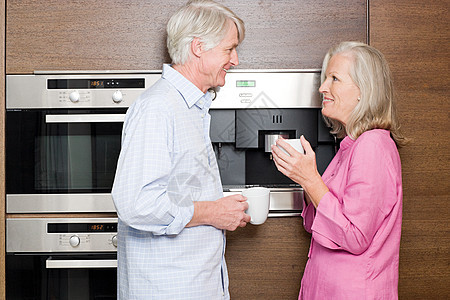 一对中年夫妇端着咖啡站在厨房里图片