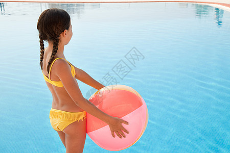 游泳池边有沙滩球的女孩图片