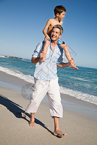 父亲肩扛在海边的男孩图片