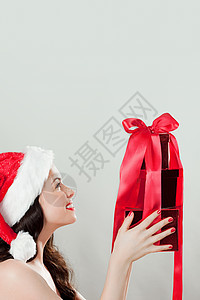 身穿圣诞帽带圣诞礼物的浅褐色年轻女子图片