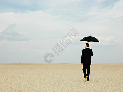 沙漠中带伞的商人图片