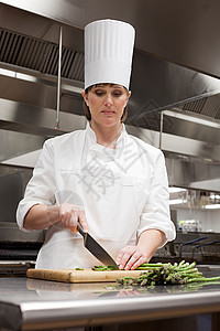 女厨师在商业厨房切芦笋背景图片