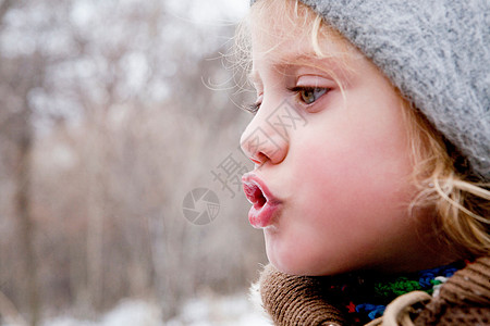 小女孩在寒冷的空气中看着她的呼吸图片