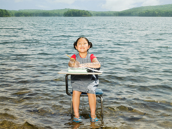 一个女孩坐在湖边的桌子旁图片