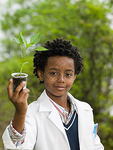 把植物放在容量瓶中的男孩图片