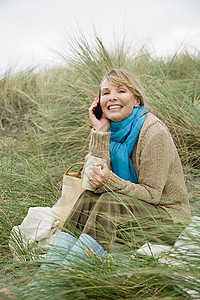 女人在沙丘上拿着杯子和手机图片
