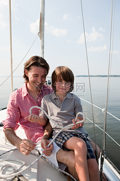 父亲和儿子在游艇上拿着绳子图片