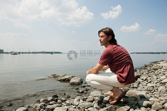 中年男子蹲在沙滩上看风景图片