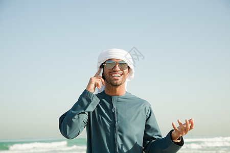 在海滩上使用手机的中东男人图片