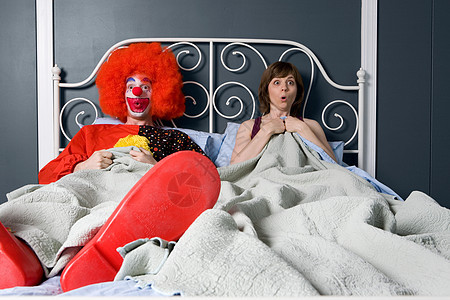小丑和女人惊奇地发现他们在床上在一起图片
